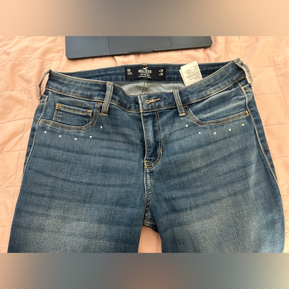 Blue Holister jeans with pink holographic gems on pockets